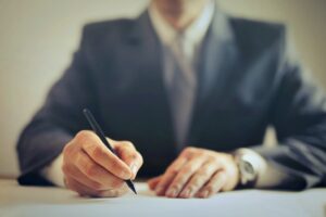 Lawyer's hands on the table, with their torso in a suit in the background